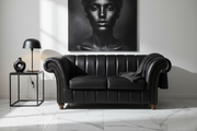 Black leather sofa in a room with a large portrait of a woman on the wall.