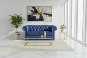 Modern living room with a blue sofa, gold coffee table, and abstract art on the wall.