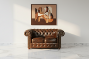 Brown leather sofa in a room with abstract art on the wall.