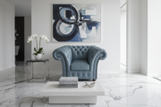 Grey armchair in a modern living room with abstract art on the wall.