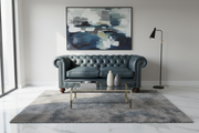 Modern living room with a gray sofa, coffee table, and abstract painting.